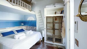 Habitación de hotel con cama, una escalera, armario y un ventanal grande.