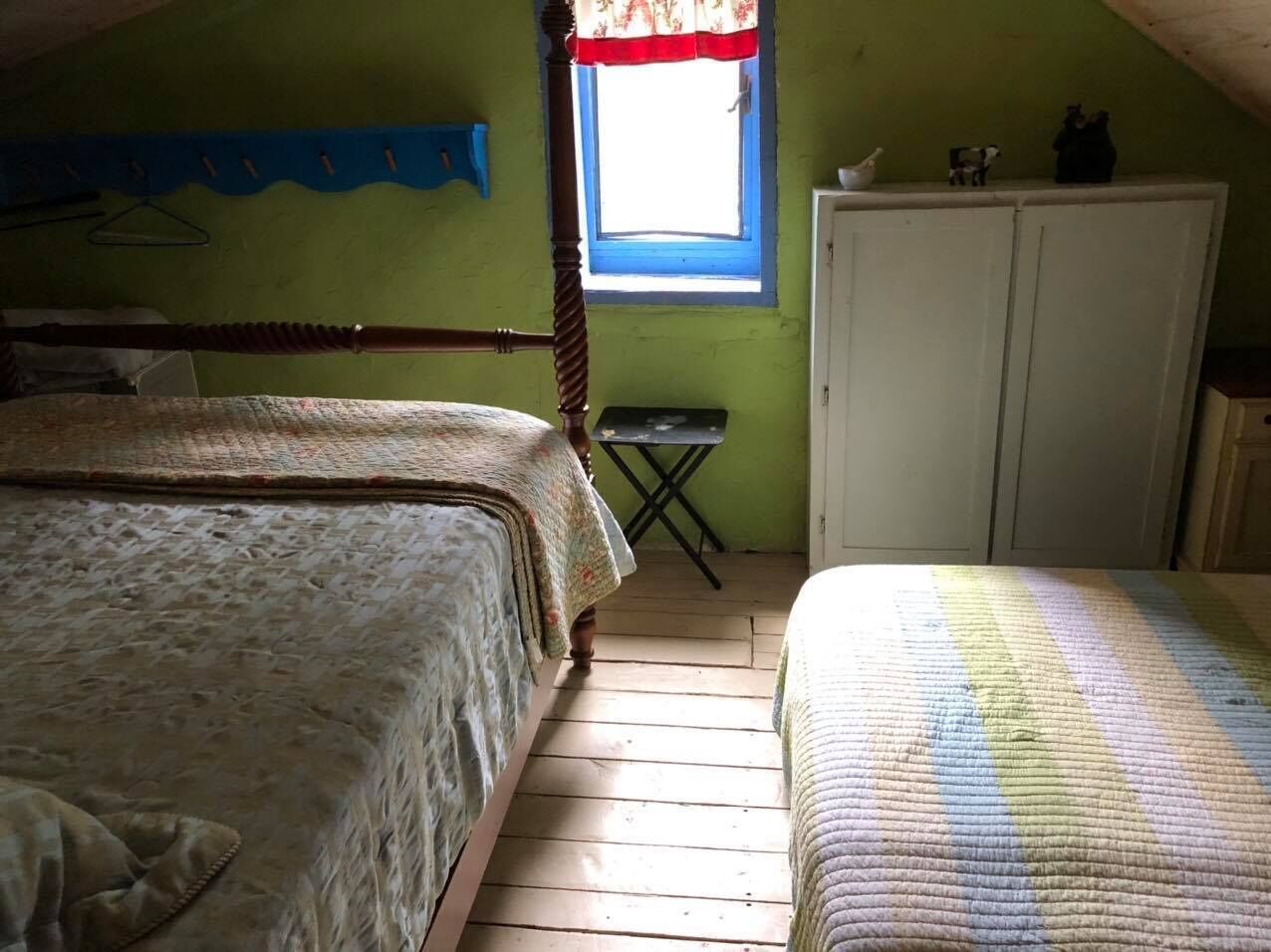 A bedroom with two beds, a window, and a small table.