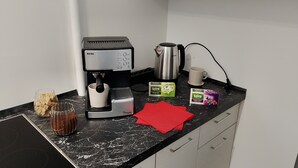 A kitchen counter with a coffee maker, a kettle, a mug, and tea boxes.