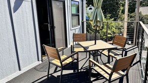 An outdoor patio with a table and chairs, a door, and a window.