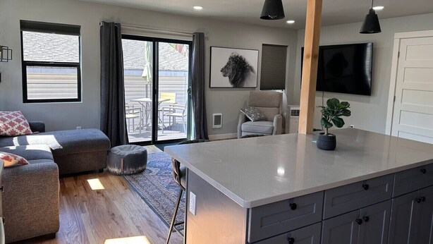 A modern kitchen with a large island, grey cabinets, and pendant lighting.