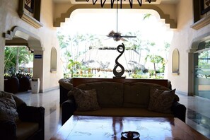A lobby with a sofa, a table with a teapot, and a ceiling fan.