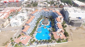 An aerial view of a hotel with multiple swimming pools, a beach, and surrounding buildings. - GRAN PACIFICO, OCEANFRONT CONDOMINIUM, MANZANILLO (Manzanillo)