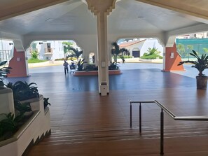 An open atrium with a central staircase, potted plants, and a view of the street outside. - GRAN PACIFICO, OCEANFRONT APARTMENT, MANZANILLO (Manzanillo)