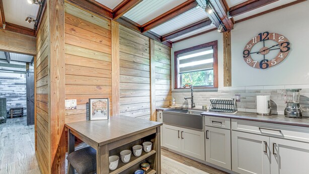 A kitchen with wooden walls, a wooden bar counter, and a large wall clock. - Farmhouse Hideaway w/ Covered Patio in Kissimmee (Kissimmee)