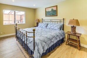 Ein Schlafzimmer mit Bett, Fenster, Gemälde und Nachttisch.