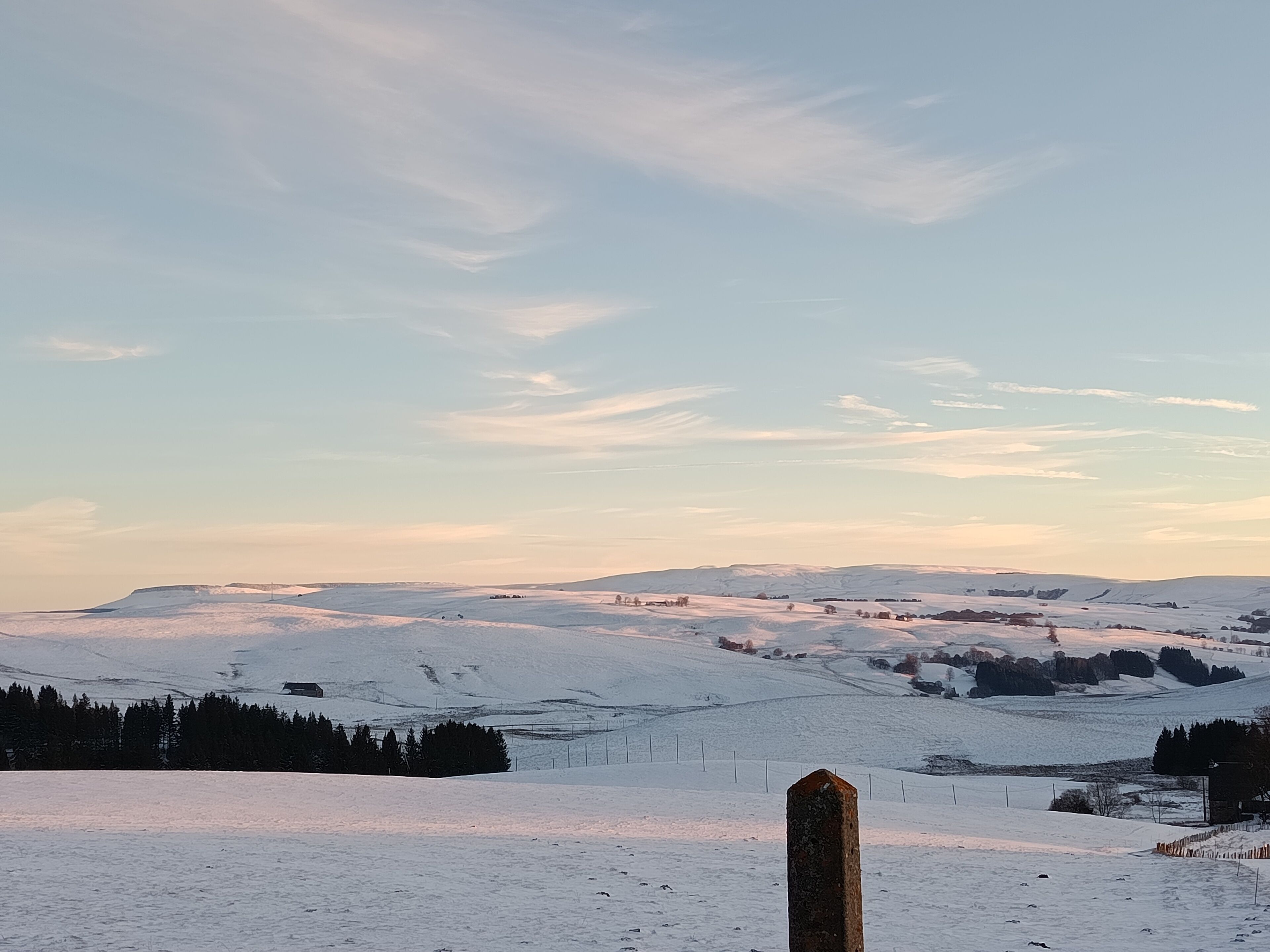 Un paysage enneigé, avec un grand repère en pierre bien visible au premier plan.