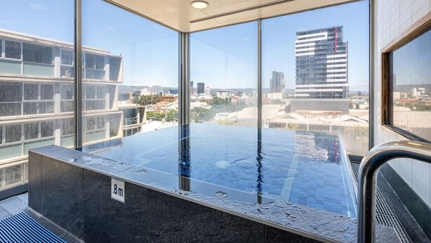 A modern indoor pool with large windows offering city views.
