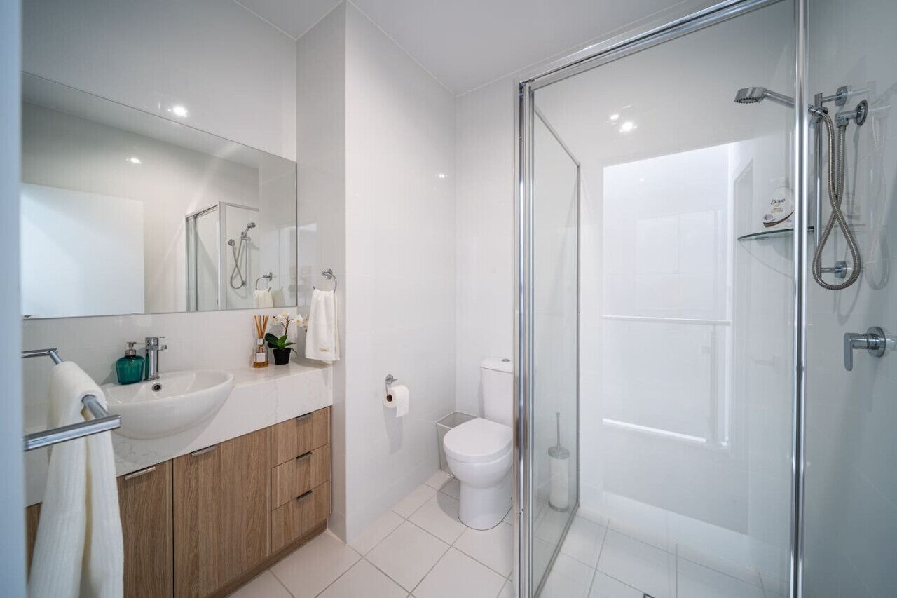A modern bathroom with a glass shower enclosure, a white sink, and a toilet.