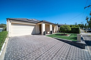 Une maison à deux étages avec un garage, une allée pavée et une pelouse bien entretenue.
