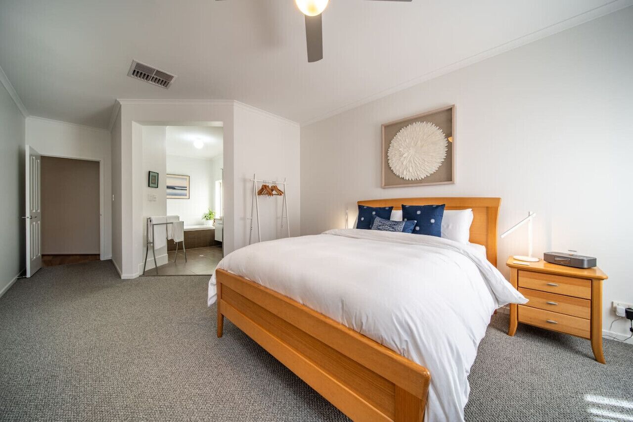 Une chambre à coucher avec un lit en bois, une table de chevet avec une lampe et une œuvre d’art accrochée au mur.