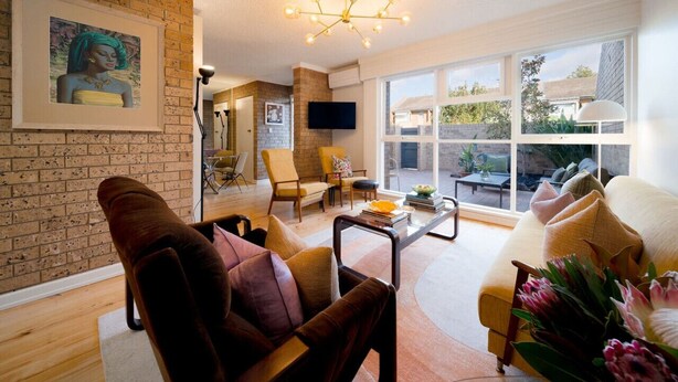 A modern living room with a brick wall, large windows, and a chandelier. - Honeyeater Hidden Gem—Stylish Courtyard in the CBD (North Adelaide)