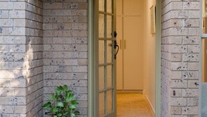 A brick exterior with a green door, a potted plant, and a tiled entrance. - Honeyeater Hidden Gem—Stylish Courtyard in the CBD (North Adelaide)