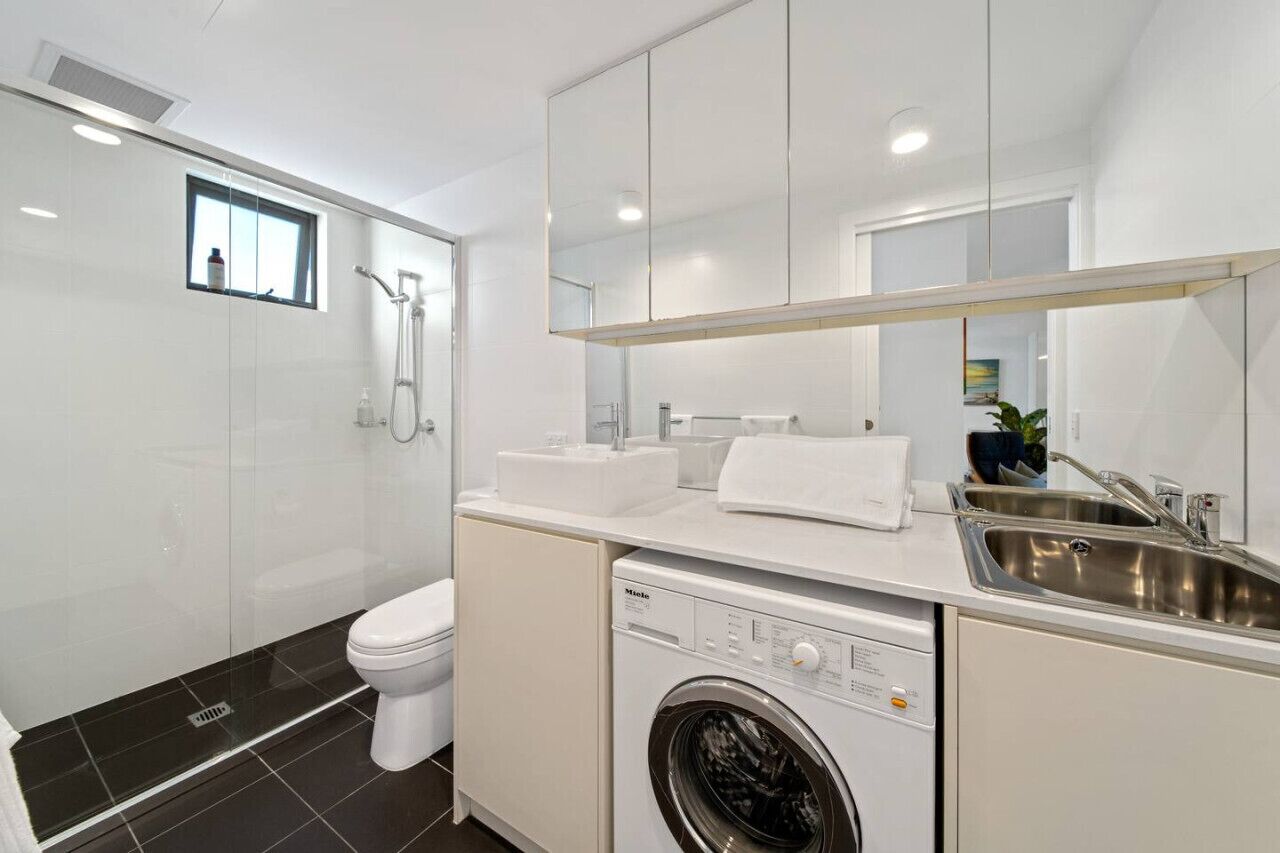 A modern bathroom with a toilet, shower, and washing machine.