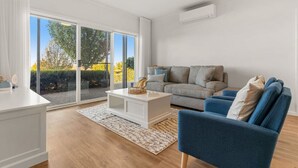 Ein modernes Wohnzimmer mit einem grauen Sofa, einem blauen Sessel und einem weißen Couchtisch.