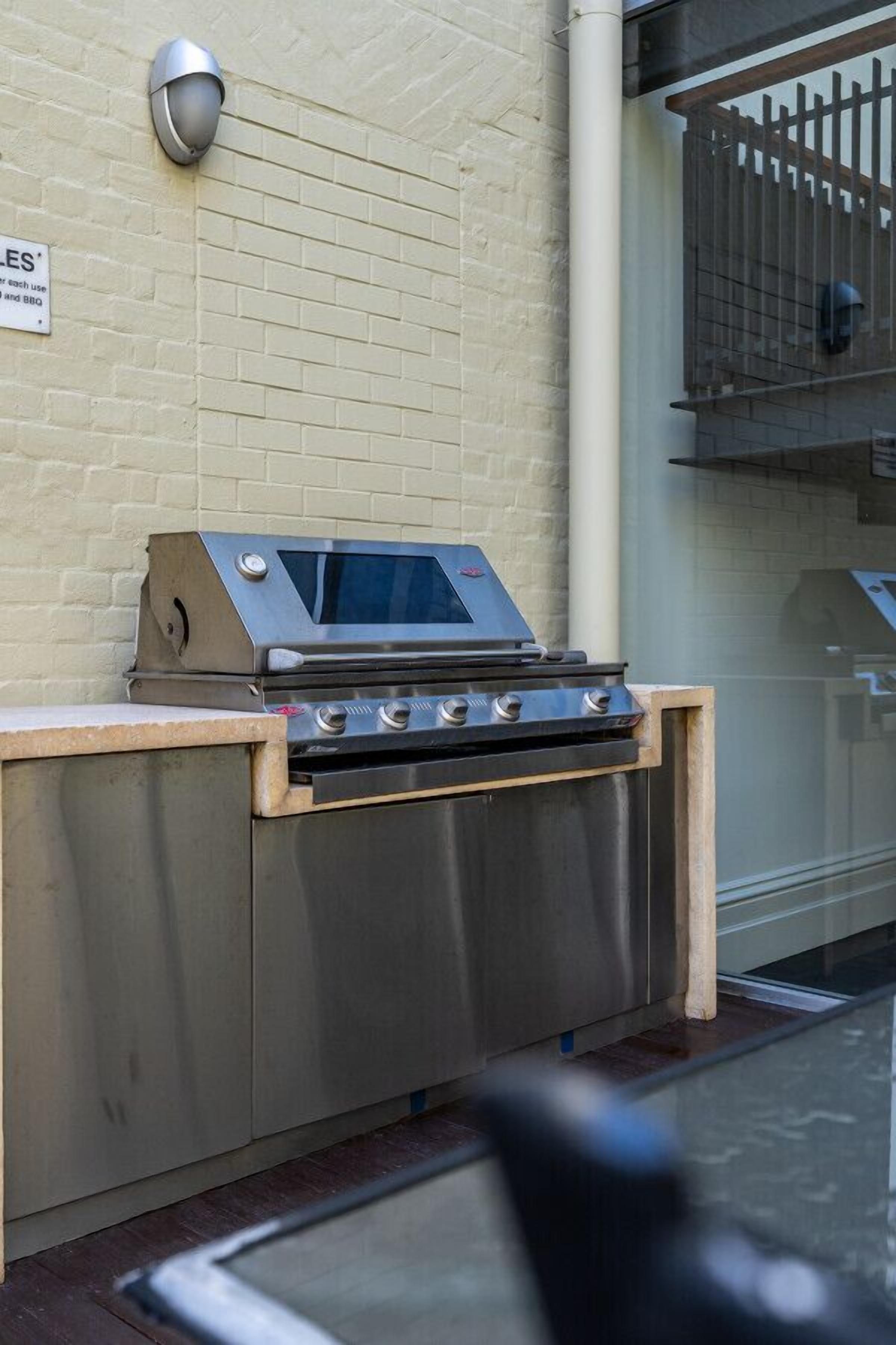 An outdoor grill with a stainless steel finish, a digital display, and a wooden countertop.