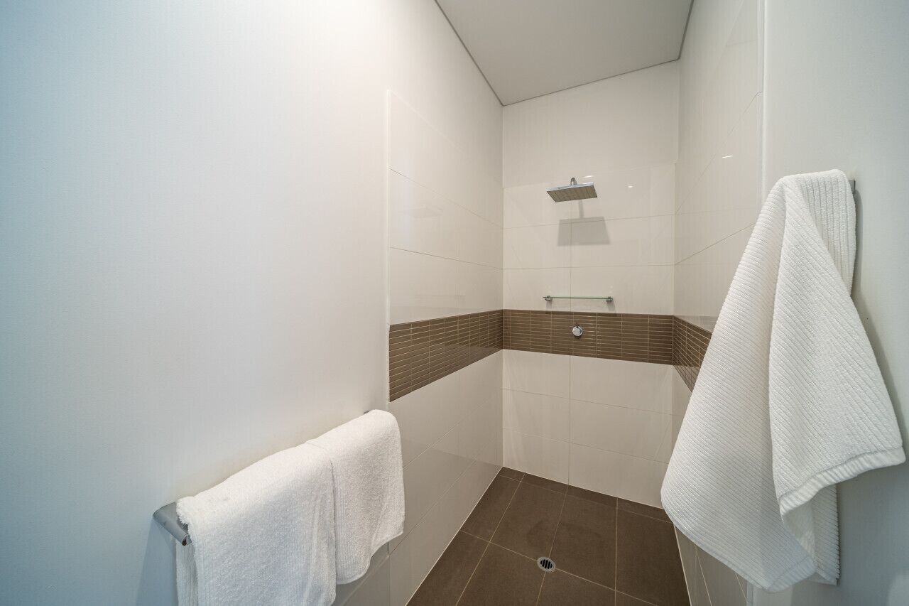 A modern bathroom with a shower, a towel rack, and a tiled floor.