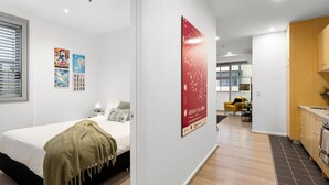 A modern hotel room with a bed, a small desk, and a view into the living area. - Artful Escape on York - Walkable Location in the CBD (Adelaide)