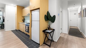 Een moderne keuken met houten kastjes, een witte koelkast, en een klein eethoekje met een tafel en stoelen.