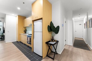 Une cuisine moderne avec des meubles en bois, un réfrigérateur blanc et un petit coin repas comprenant une table et des chaises.