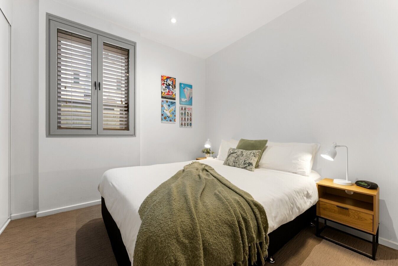 A bedroom with a bed, bedside tables, a lamp, and wall art.