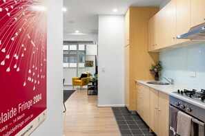 A modern kitchen with wooden cabinets, a stainless steel sink, and a gas stove. - Artful Escape on York - Walkable Location in the CBD (Adelaide)