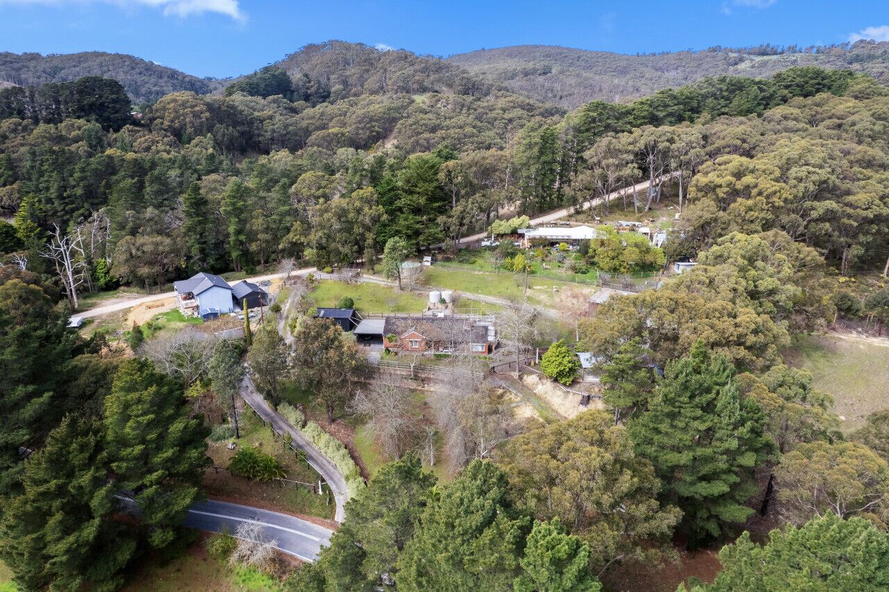 Vista aérea de una zona rural con casas dispersas, rodeada de bosques densos y colinas.