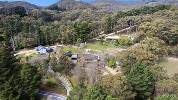 Vista aérea de una zona rural con casas dispersas, rodeada de bosques densos y colinas.
