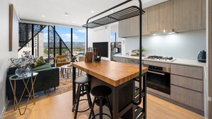 A modern kitchen with a wooden countertop, stainless steel appliances, and a view of the city through large windows.