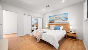 Une chambre à coucher avec un grand lit, une tête de lit en bois, des tables de chevet et un tableau au mur.