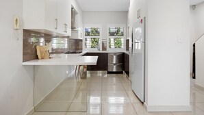 A modern kitchen with a central island, stainless steel appliances, and a view of greenery outside.