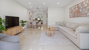 A modern living room with a sofa, TV, and dining area.