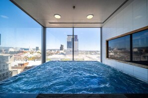 A hot tub with a city view, large windows, and a modern interior.