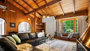 A cozy living room with a black leather sofa, a glass coffee table, and a wooden ceiling. - Amber Wisper—In the Hills with Pool & Tennis Court (Paechtown)