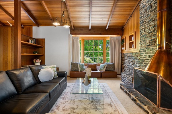 Unwind by the fireplace in a warm, timber-lined living space designed for relaxed evenings.