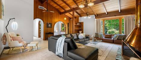 Un salón amplio con chimenea, sofás de cuero y un techo alto con vigas a la vista.