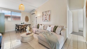 Un salon moderne comprenant un canapé, une table basse et un coin repas avec des chaises et une table.