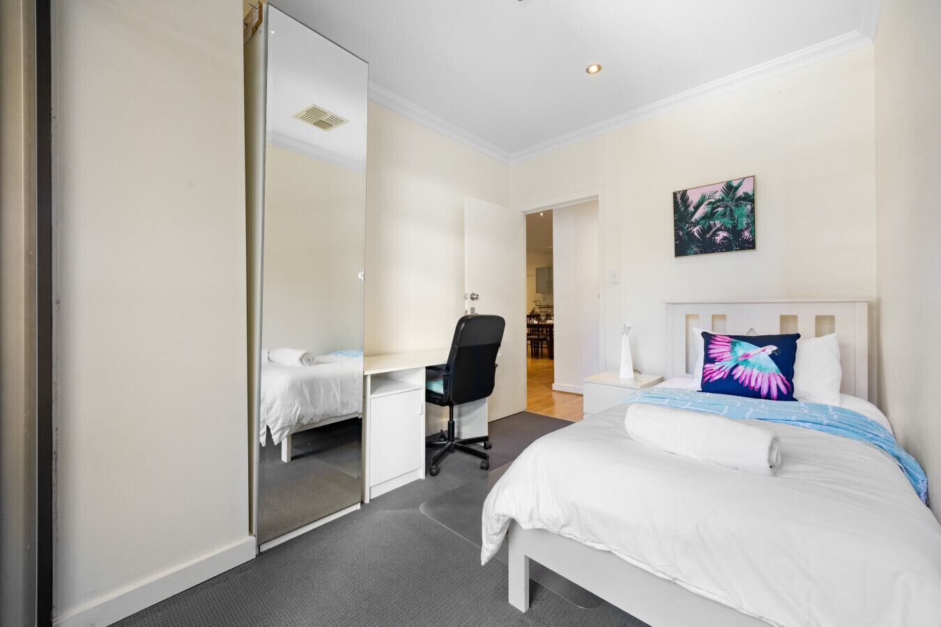 Une chambre d’hôtel avec un lit, un bureau, une chaise et un miroir.