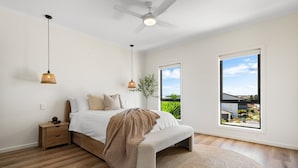 Una camera da letto con un letto, comodini, un ventilatore a soffitto e ampie finestre che offrono vista sull'esterno.
