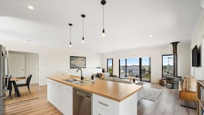 Una cucina moderna con lavastoviglie, zona pranzo con tavolo e sedie, e un'ampia finestra con vista all'esterno.