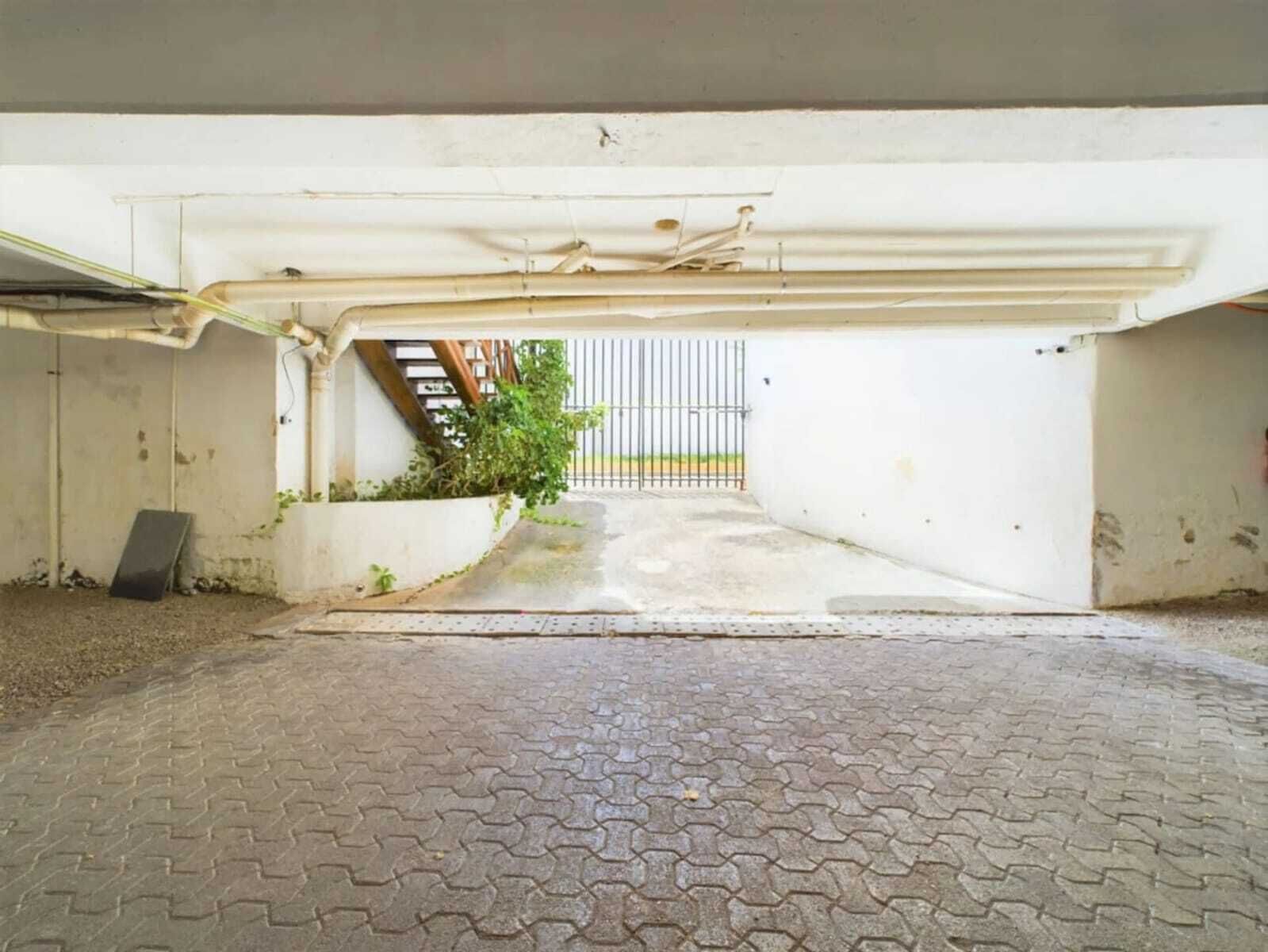 An empty parking garage with concrete walls, a metal gate, and a paved entrance.