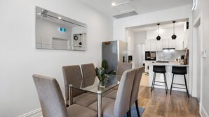 Una cucina moderna con mobili bianchi, un frigorifero in acciaio inossidabile e un forno integrato.