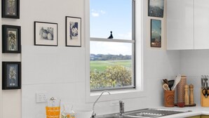 Une cuisine moderne dotée d’une grande fenêtre, de meubles blancs et offrant une vue sur un paysage.