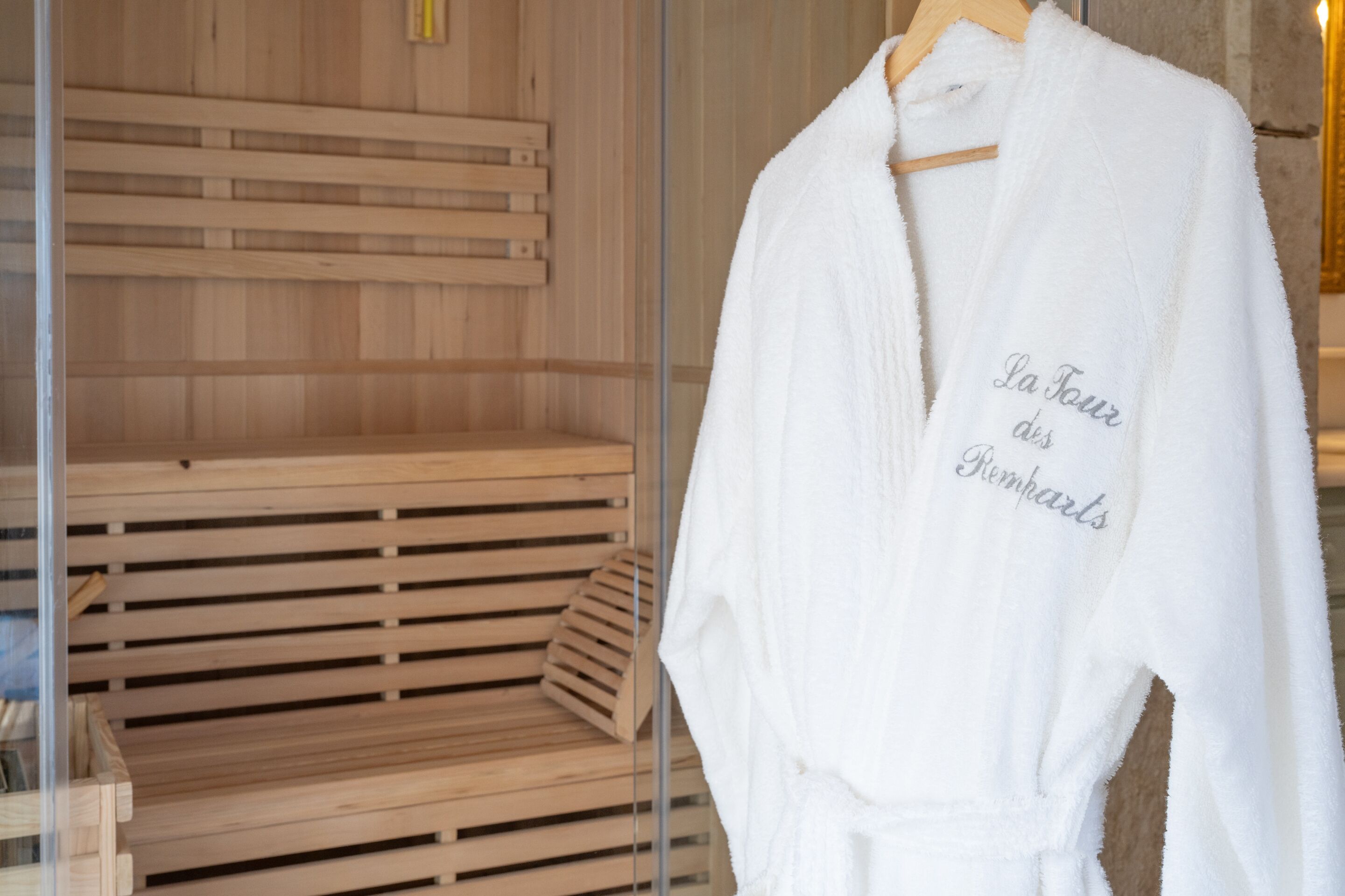 Une blouse blanche, ornée de motifs, est suspendue à un portant dans une pièce en bois.