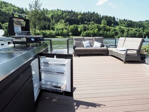 Een terras met een barbecue, een bank en een koelkast.