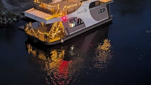 Une péniche dotée d’une terrasse et d’une partie couverte, toutes deux illuminées par des guirlandes lumineuses.
