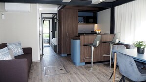 Une cuisine moderne avec un coin bar, une table à manger avec des chaises et un canapé avec des coussins.