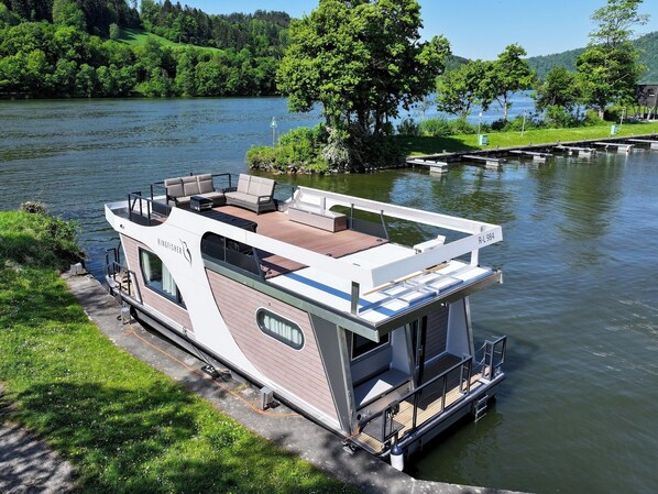 Een woonboot met een dek, zitgedeelte en een kitchenette.