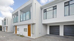 A modern residential building with a flat roof, large windows, and a paved driveway. - Quiet Suburban Escape Near Shops & Dining (Blair Athol)