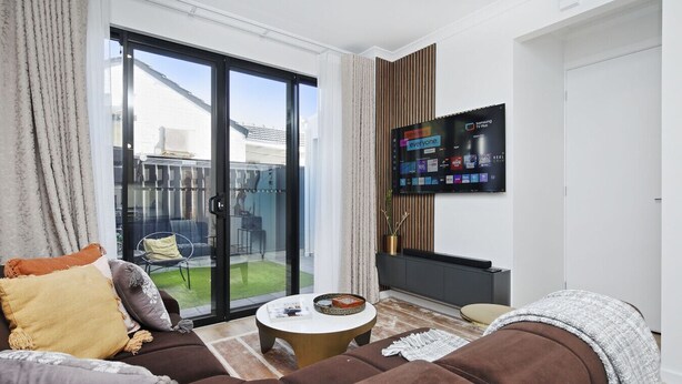 A modern living room with a sofa set, a coffee table, and a flat-screen TV mounted on the wall. - Quiet Suburban Escape Near Shops & Dining (Blair Athol)